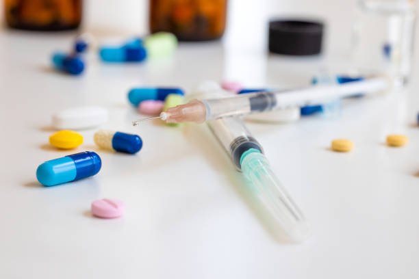 Syringe and pills on table